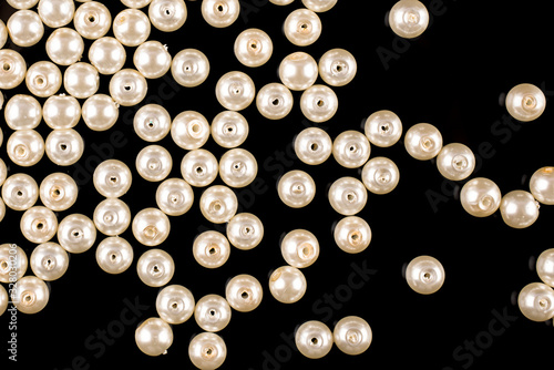A scattering of beige pearl beads on a black background