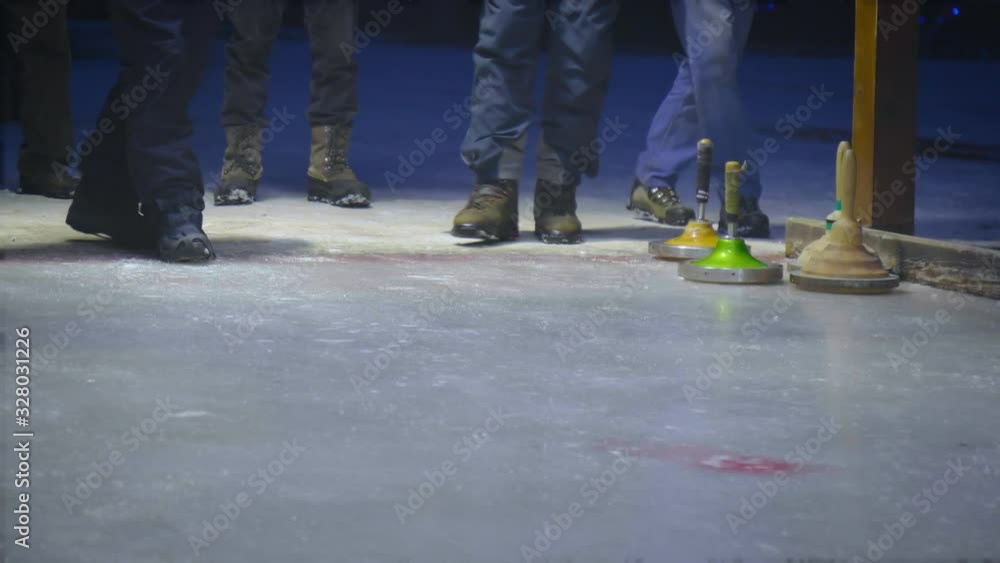 People throwing curling stone on the ice. People throwing curling stone on the ice.
