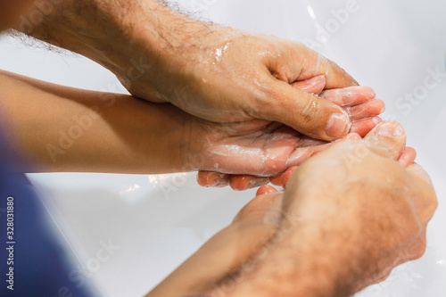  Dad washing his little son's hands with soap and water