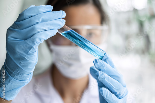 Scientist or medical in lab coat holding test tube with reagent  Laboratory glassware containing chemical liquid  Microscope  Biochemistry laboratory research