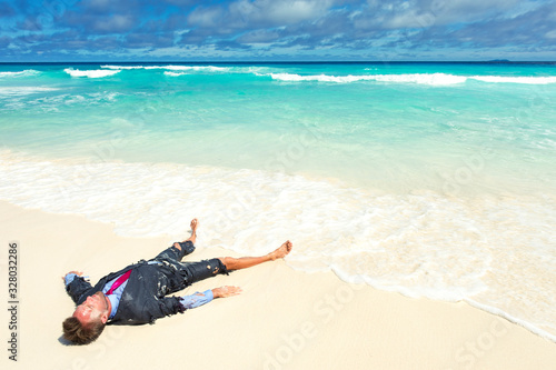 Castaway office worker washed up on a tropical beach in a ragged torn suit