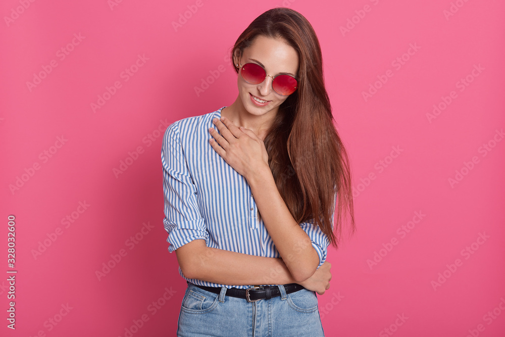 Φωτογραφία Fashionable young woman wearing jeans, blouse and glasses, posing isolated over pink background