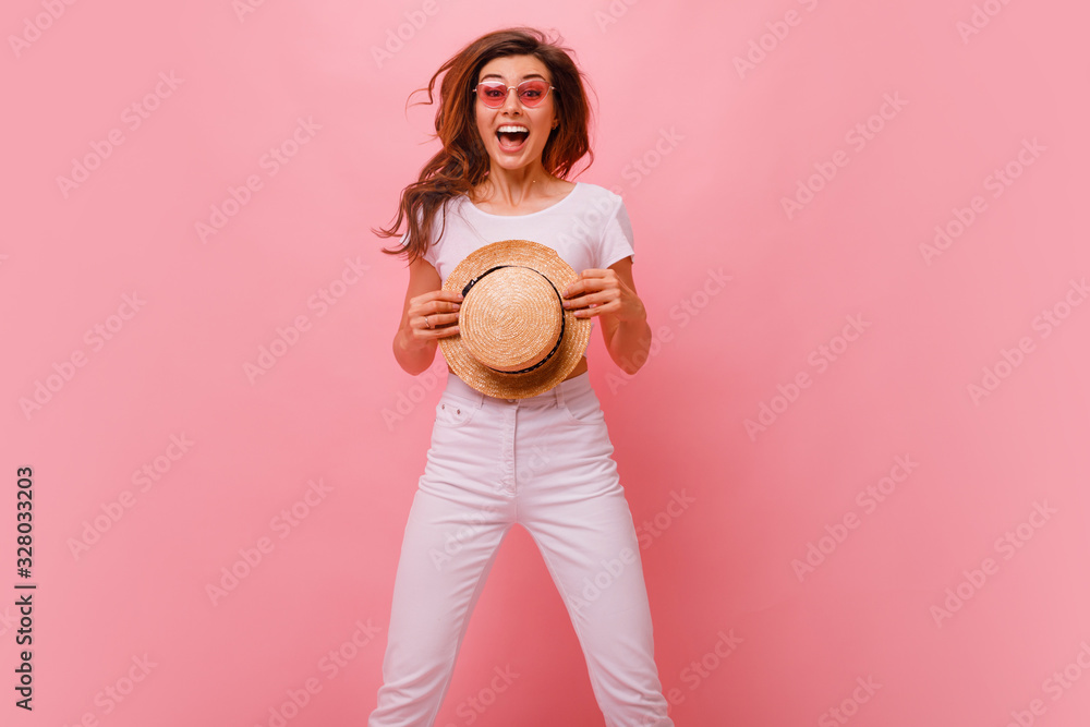 Inspired european young woman dancing in studio and laughing. Winsome brunette girl in white jeans and white t shirt jumping on pink background. Inspired european young woman dancing in studio and laughing. Winsome brunette girl in white jeans and white t shirt jumping on pink background.