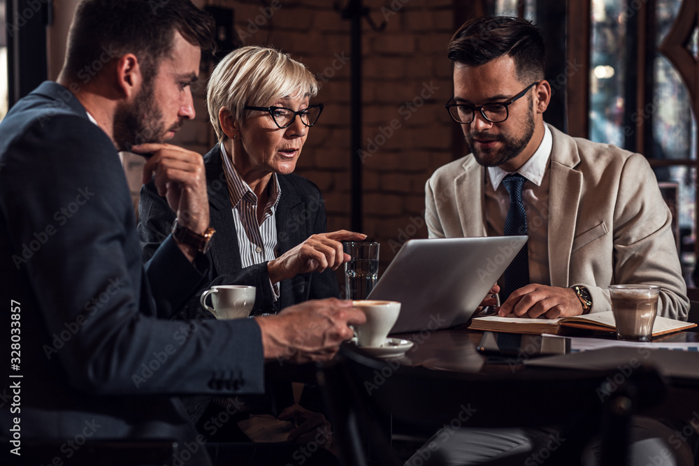Senior businesswoman holding a casual meeting with her younger colleagues in coffee shop. Senior businesswoman holding a casual meeting with her younger colleagues in coffee shop.