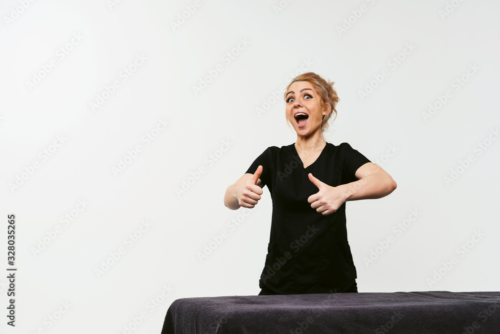 Φωτογραφία Portrait of young cheerful friendly woman masseur in uniforme near massage table in wellness center