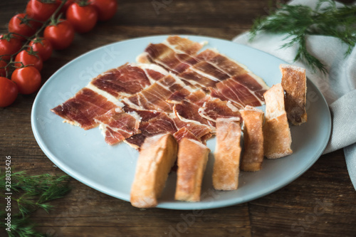 Top view  Prosciutto platter with baguette on wooden table with ingredients around