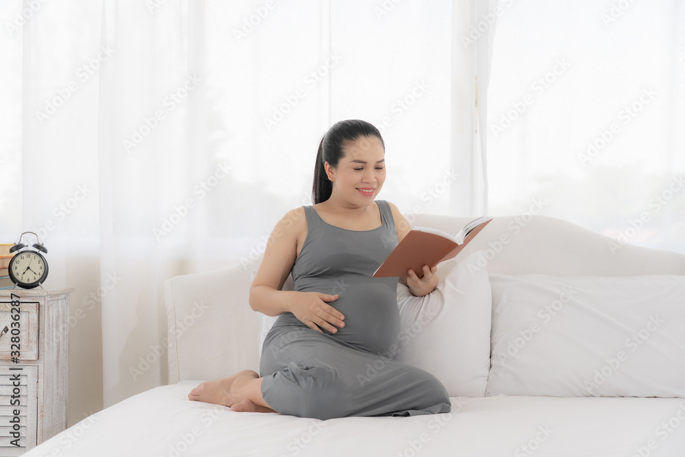 Happy Asian pregnant are reading a book in bedroom Happy Asian pregnant are reading a book in bedroom