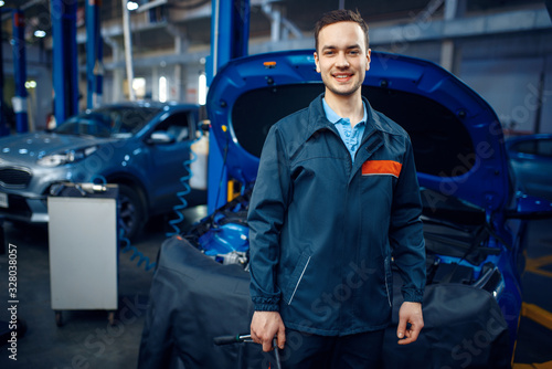 Repairman at vehicle with opened hood, car service