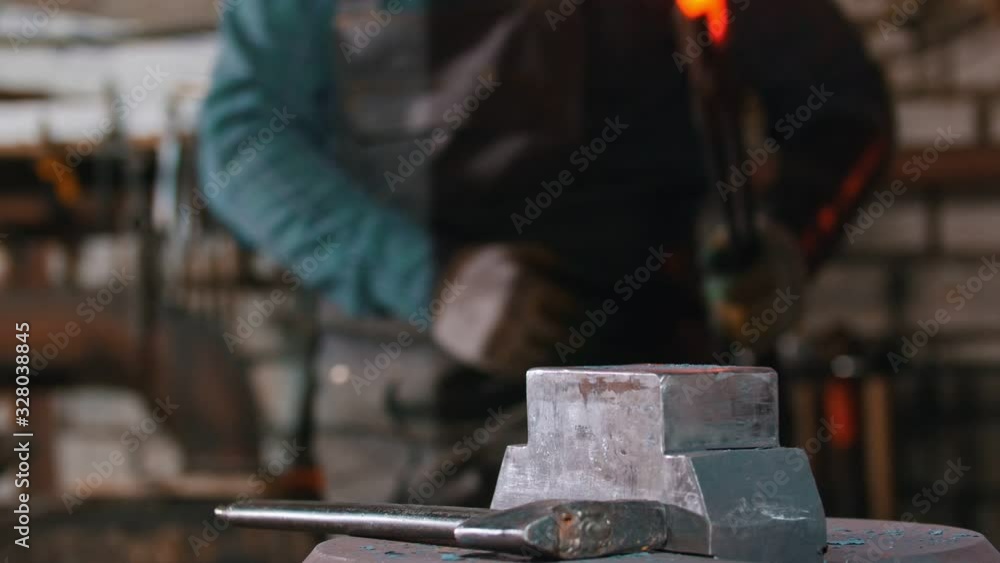 Blacksmith brings the piece of hot metal to the anvil Blacksmith brings the piece of hot metal to the anvil