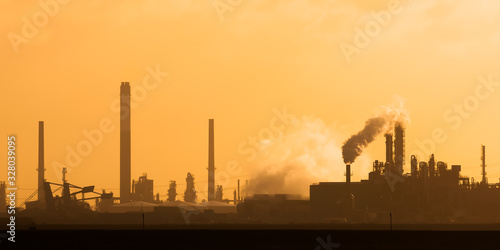 Dutch industrial plant with chimneys and windmill during sunset in Europoort, Rotterdam photo