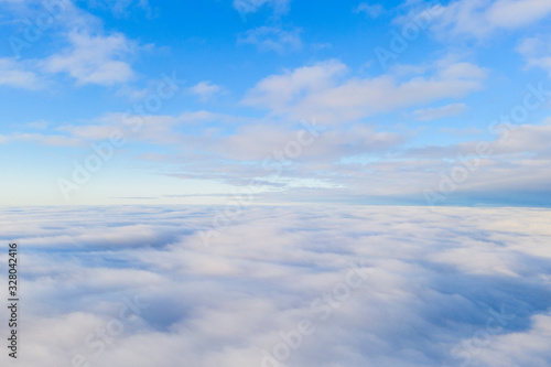 Aerial view White clouds in blue sky with solar halo. Top view. View from drone. Aerial bird's eye view. Aerial top view cloudscape. Texture of clouds. View from above. Sunrise or sunset over clouds