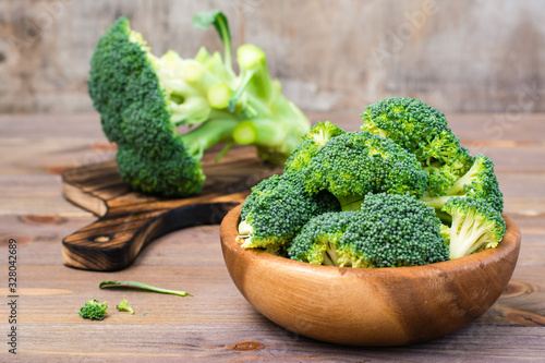 Ready to eat fresh raw broccoli is divided into inflorescences in a wooden plate on a wooden table. Healthy lifestyle, nutrition and zero waste concept