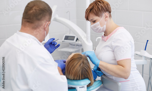 Doctor dentist treats teeth of a beautiful young girl patient.