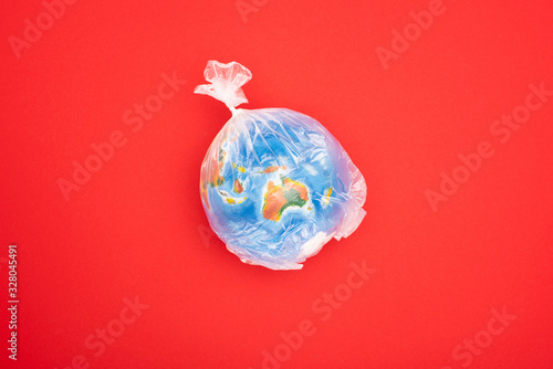 Top view of globe in plastic bag isolated on red, global warming concept