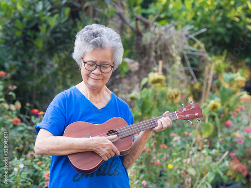Cuadro en lienzo Portrait of elderly woman playing ukulele in her garden
