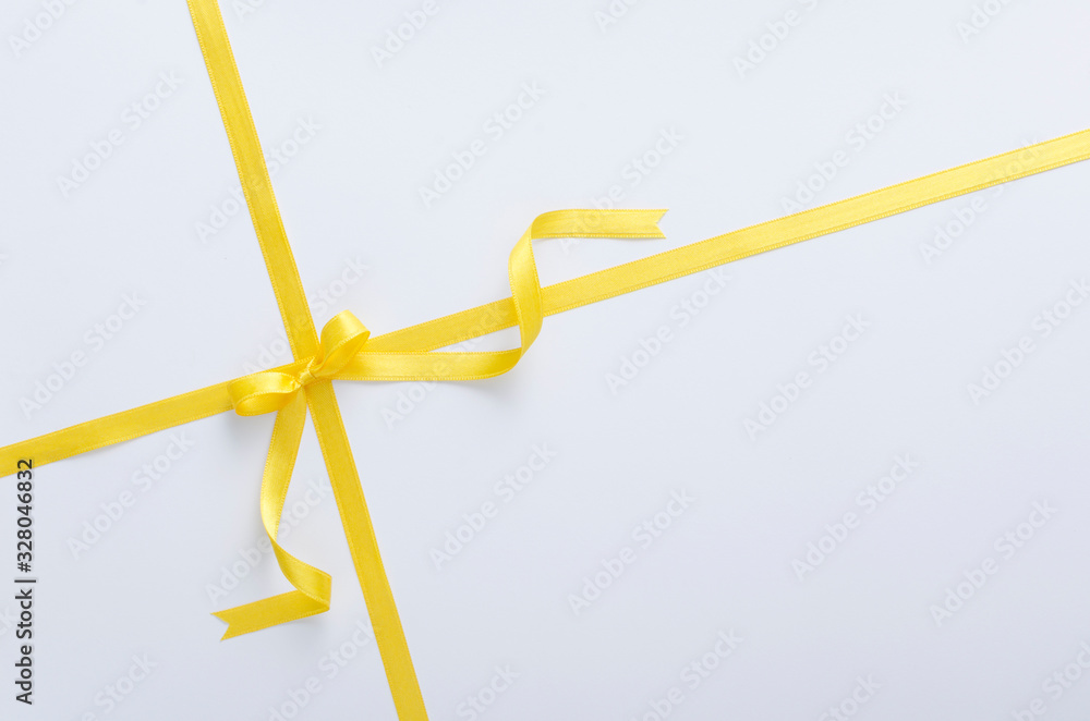 Bright yellow ribbon and bow, white surface.Gift and presents symbol.Empty space for text