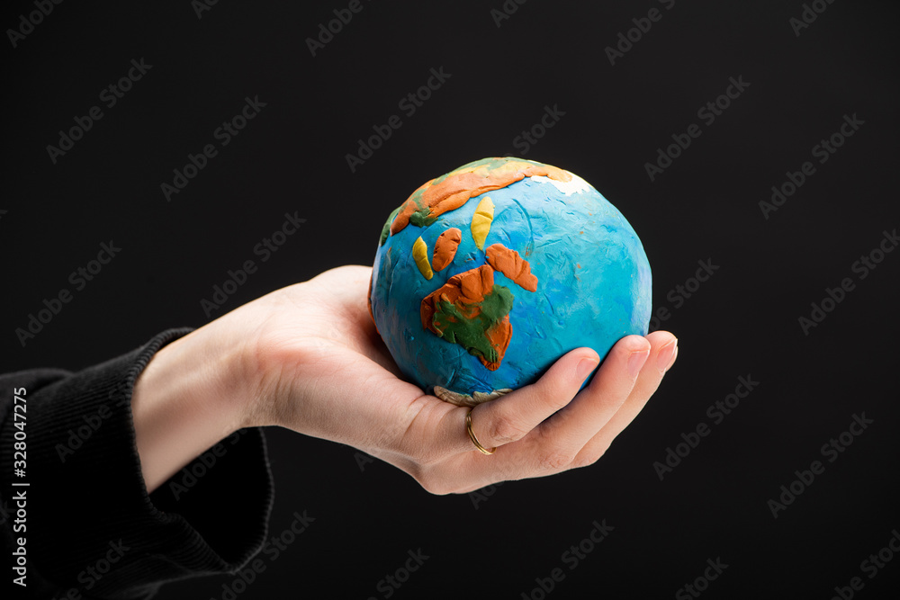 Partial view of plasticine globe in female hand isolated on black, global warming concept Partial view of plasticine globe in female hand isolated on black, global warming concept
