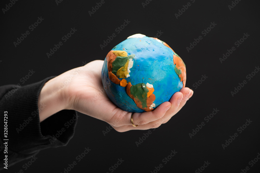 Cropped view of plasticine globe in female hand isolated on black, global warming concept Cropped view of plasticine globe in female hand isolated on black, global warming concept
