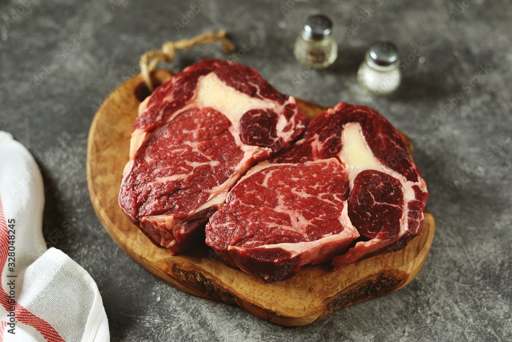 Fresh raw rib eye steak on a wooden board. Organic food. Fresh raw rib eye steak on a wooden board. Organic food.
