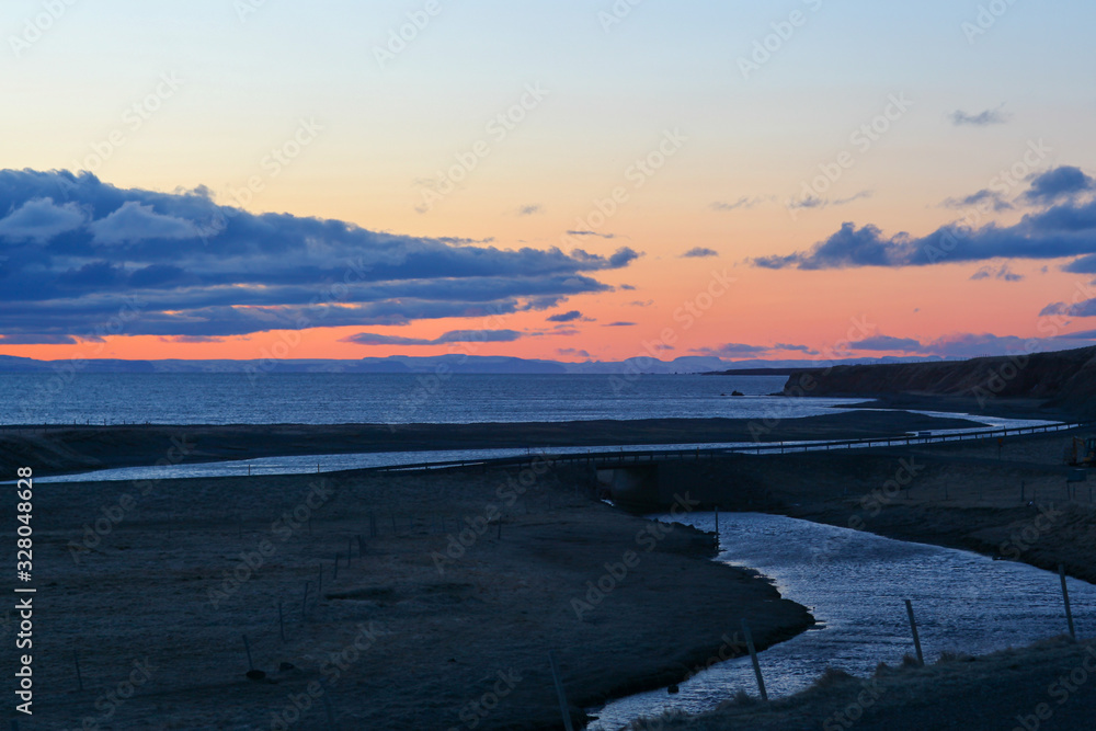 Beautiful sunset over the ocean with waves moving to shore on the North Shore of Iceland.