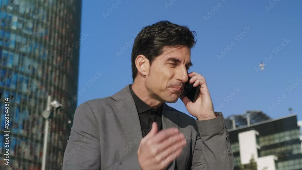 Businessman talking mobile phone at street. Executive celebrating success Businessman talking mobile phone at street. Executive celebrating success