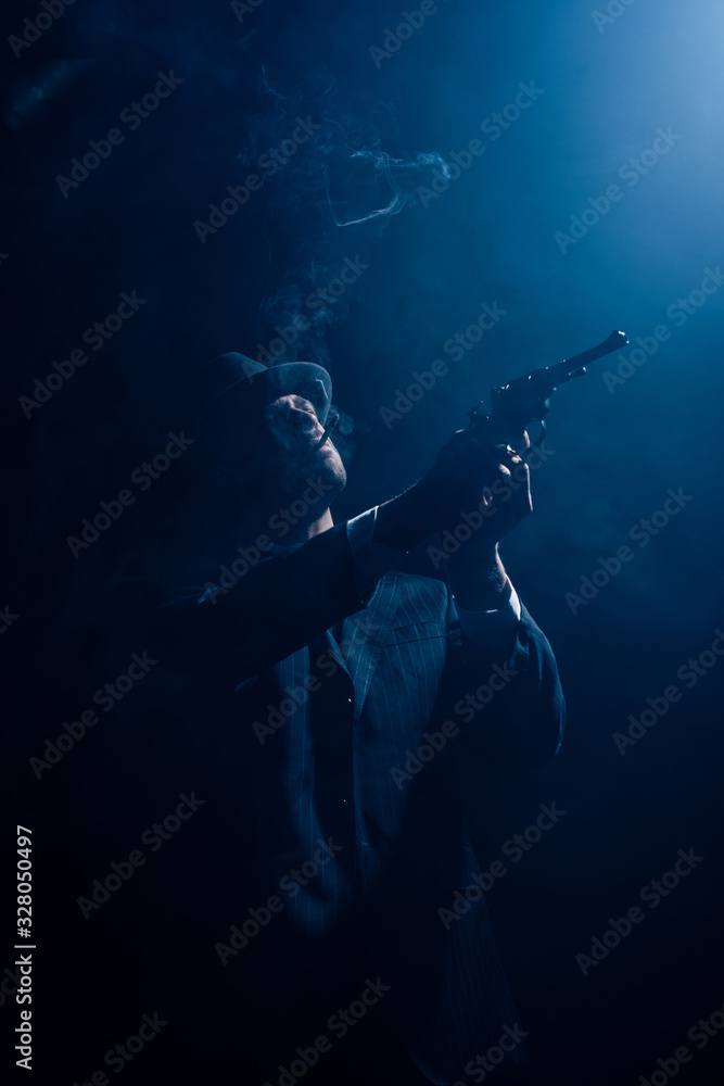 Silhouette of gangster aiming gun and smoking on dark blue background