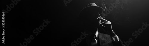 Monochrome image of mafioso silhouette smoking on black background, panoramic...
