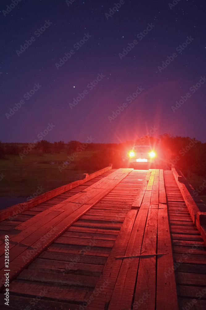 carro sobre ponte da estrada do Pantanal ao anoitecer