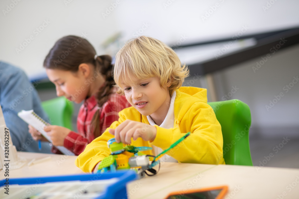 Boy playing with buildable bird, girl checking notes
