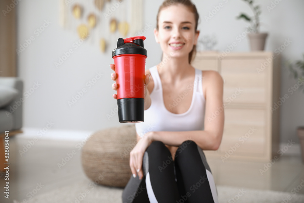 Sporty young woman with protein shake at home