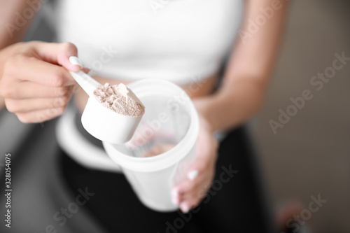 Sporty young woman with protein at home, closeup photo