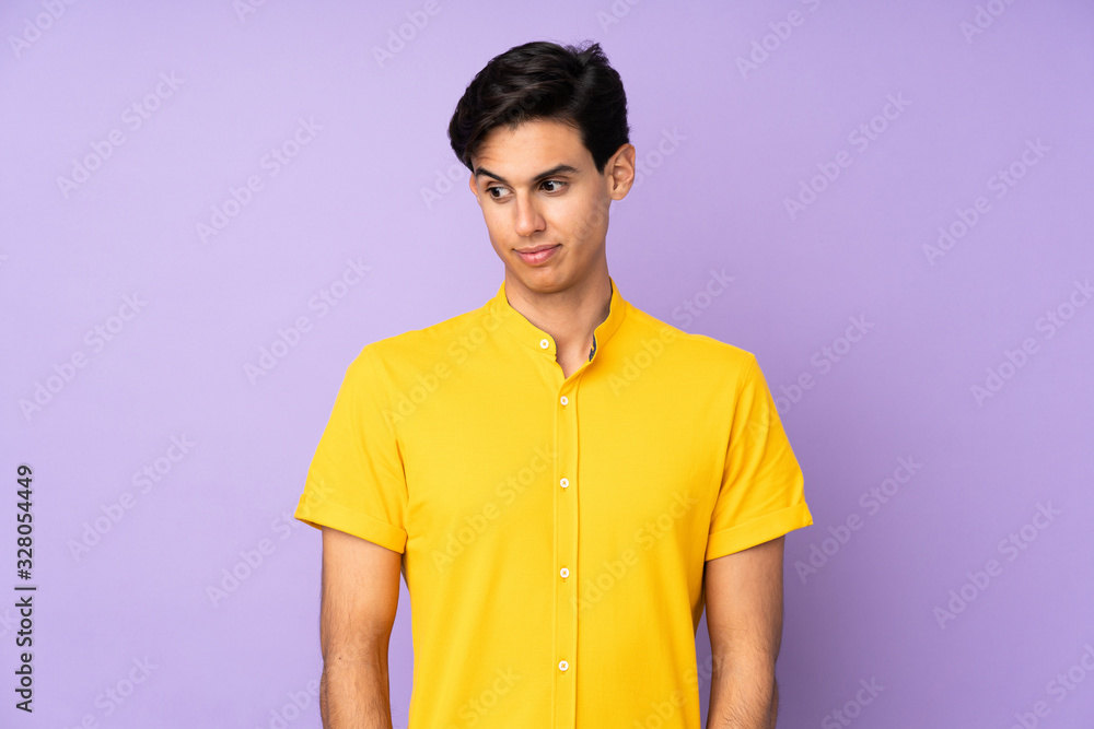 Man over isolated purple background making doubts gesture looking side Man over isolated purple background making doubts gesture looking side