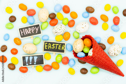 Fototapeta Naklejka Na Ścianę i Meble -  Happy easter card. Red Ice cream cone with chocolate candies and small easter eggs. Inscription: happy easter. Concept: easter, candy firework. Card. Blue background.  Close up. 