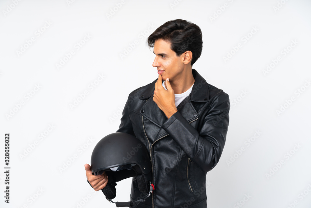 Man holding a motorcycle helmet over isolated white background thinking an idea Man holding a motorcycle helmet over isolated white background thinking an idea