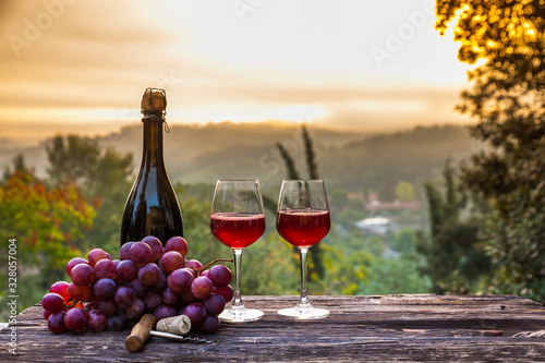 Wine Glasses And Bottle In Vineyard At Sunset