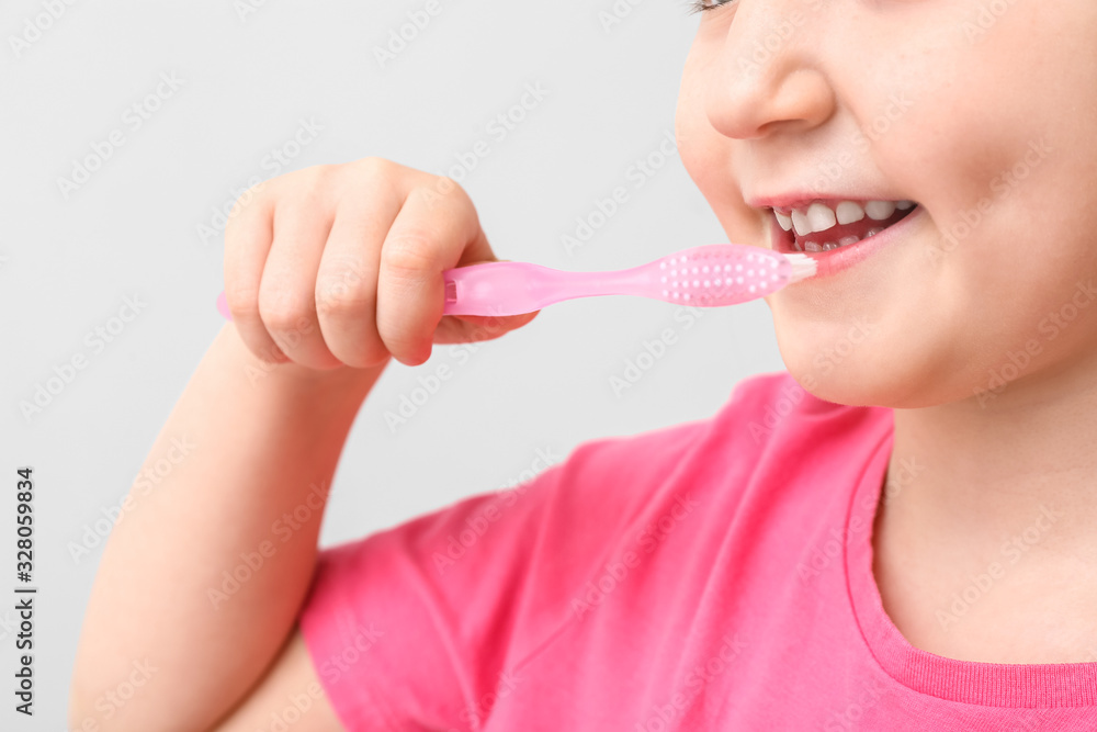 Little girl with tooth brush on light background, closeup Little girl with tooth brush on light background, closeup
