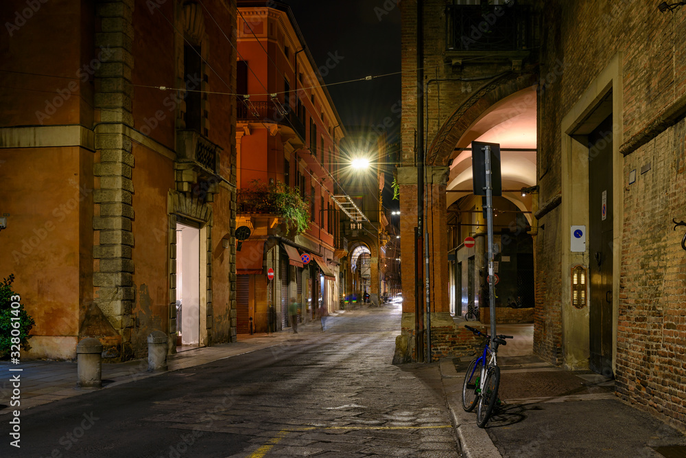 Fototapeta premium Old narrow street in Bologna at night, Emilia Romagna, Italy. Architecture and landmark of Bologna. Cozy cityscape of Bologna.