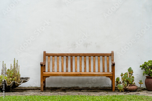 Wooden bench front of a white wall