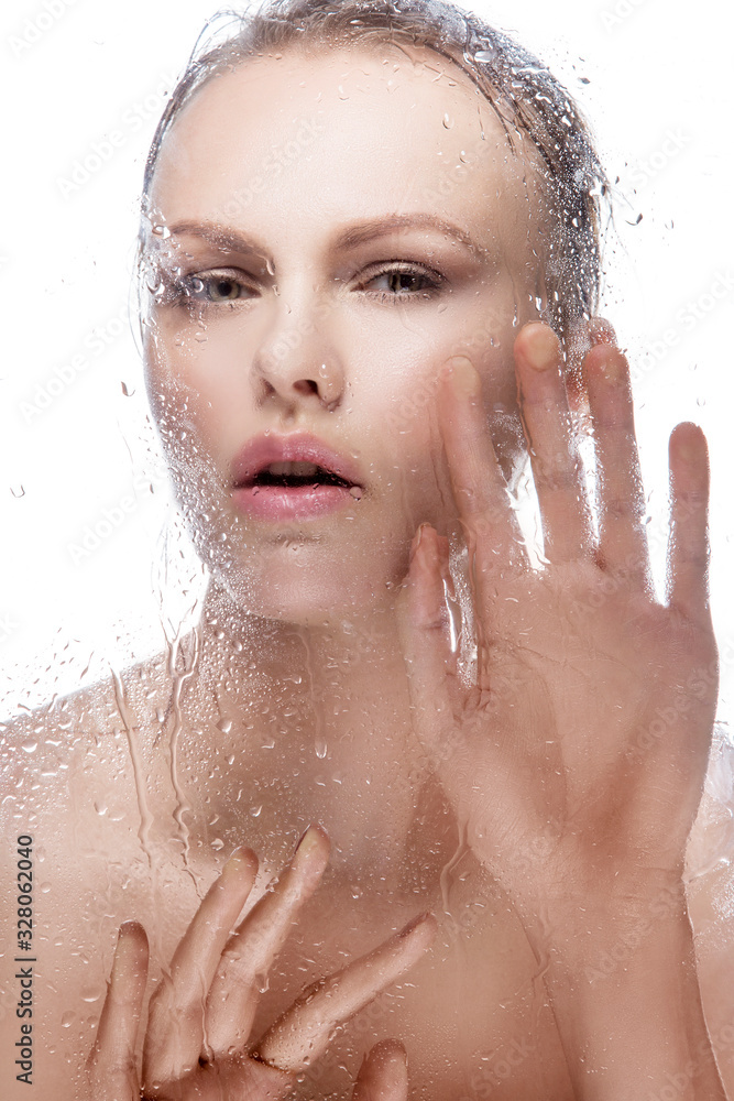 Naklejka premium Beautiful young woman wet skin, hair in spa, hands near mirror, perfect skin, watter drops on glass, beautiful hands