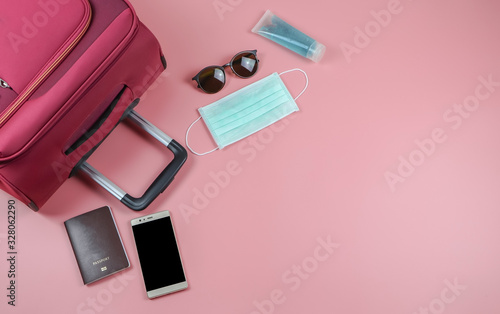 flat lay of traveli with face mask and sanitizer on pink background ,protection from corona virus or COVID-19 during traveling concept with copy space