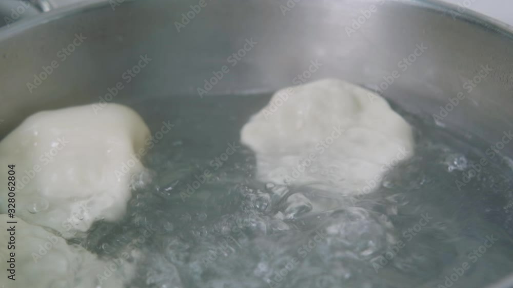 Georgian cuisine. Khinkali or dumplings are boiling in boiled water on the stove in a saucepan. Cooking process close up Georgian cuisine. Khinkali or dumplings are boiling in boiled water on the stove in a saucepan. Cooking process close up