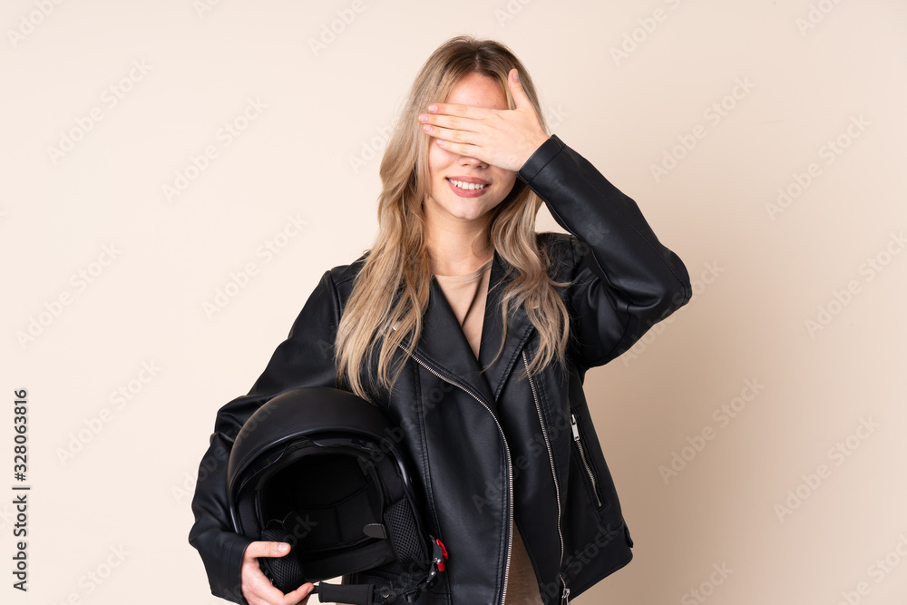 Russian girl with a motorcycle helmet isolated on beige background covering eyes by hands Russian girl with a motorcycle helmet isolated on beige background covering eyes by hands