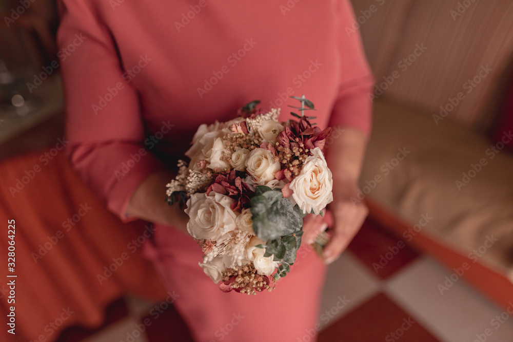 Elderly woman holding a wedding bouquet. Gold weddings. Colorful floral bouquet.