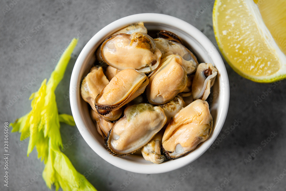 pickled mussels in a white plate with lime and a sprig of celery on a gray background, pickled mussels in a white plate with lime and a sprig of celery on a gray background,