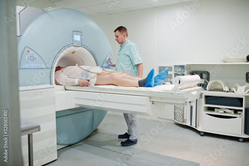 Male doctor turns on magnetic resonance imaging machine with patient inside.
