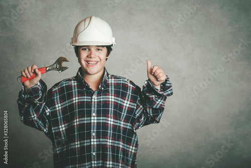 smiling boy with a white helmet and holding a wrench