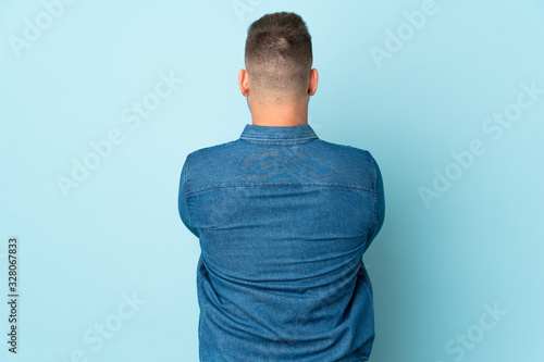 Russian handsome man isolated on blue background in back position