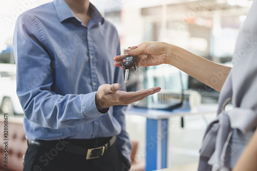 Concept car rental service. Close up view hands of agent giving car key to client that rent a vehicle in rental office.