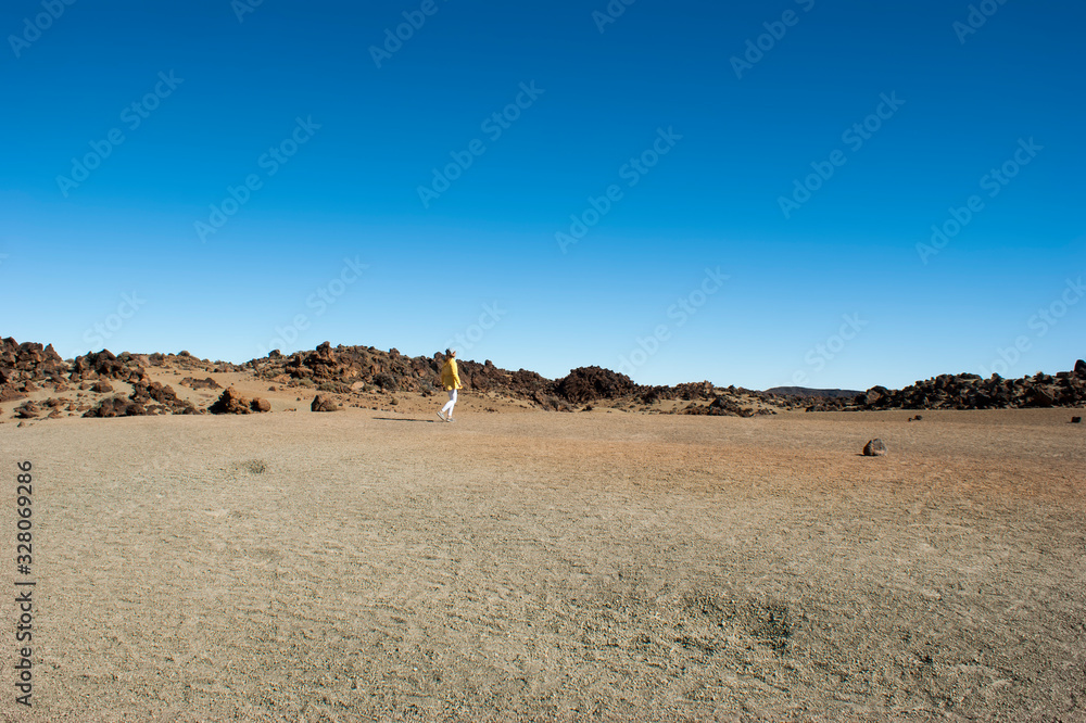 Landscape of the ancient Caldera of the Teide volcano. A girl in yellow is walking in the distance.