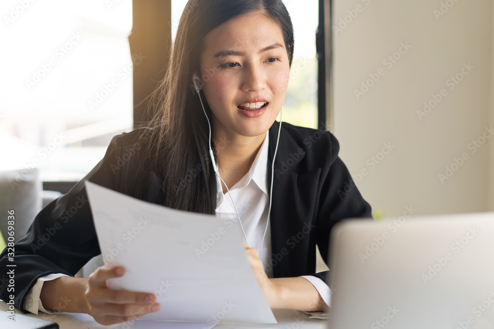 Asian young business woman holding paperwork and video calling via laptop talk to assistant in cafe. Asian young business woman holding paperwork and video calling via laptop talk to assistant in cafe.